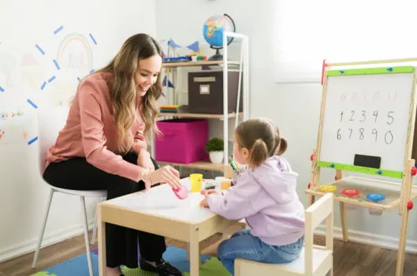 Registered Behavior Technician teaching a young girl at a kids table.