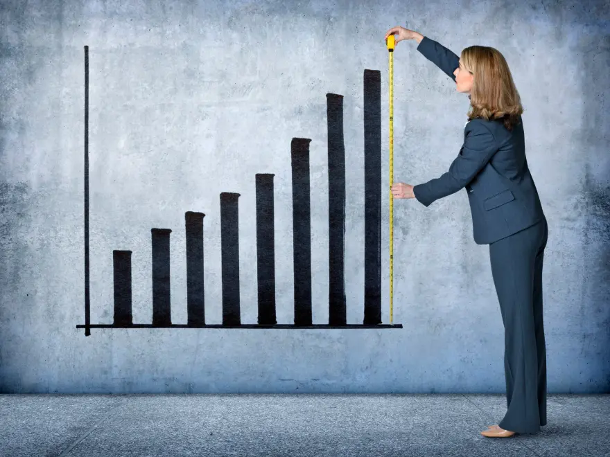 Woman standing next to a graph measuring the last bar.