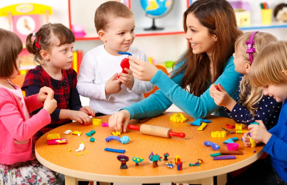 A group of kids and their teacher playing with play-dough together.