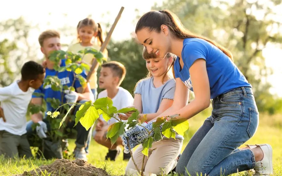 A group of kids with their teacher gardening outside.